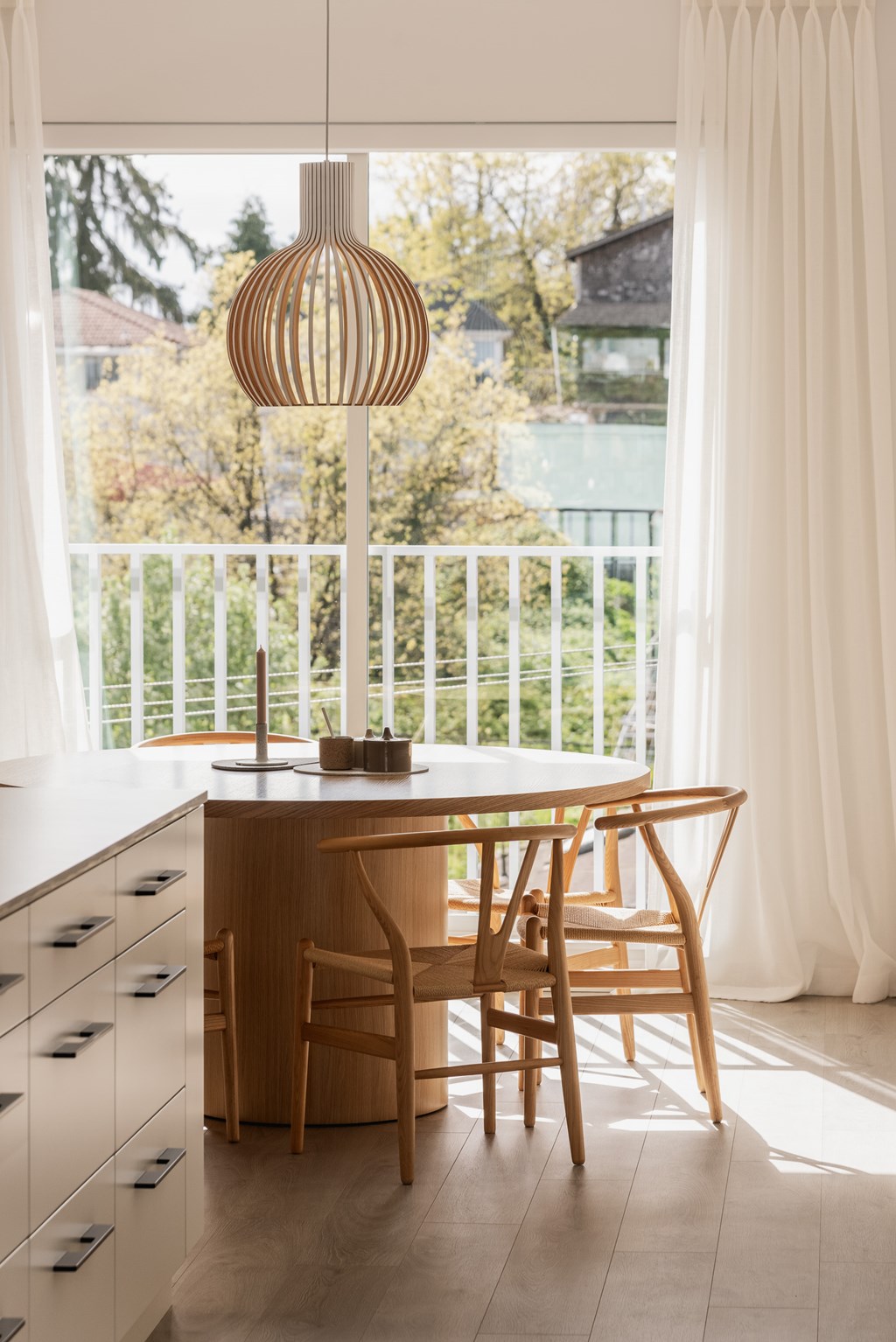 A wooden chair and table are in front of a window with a view of a garden.