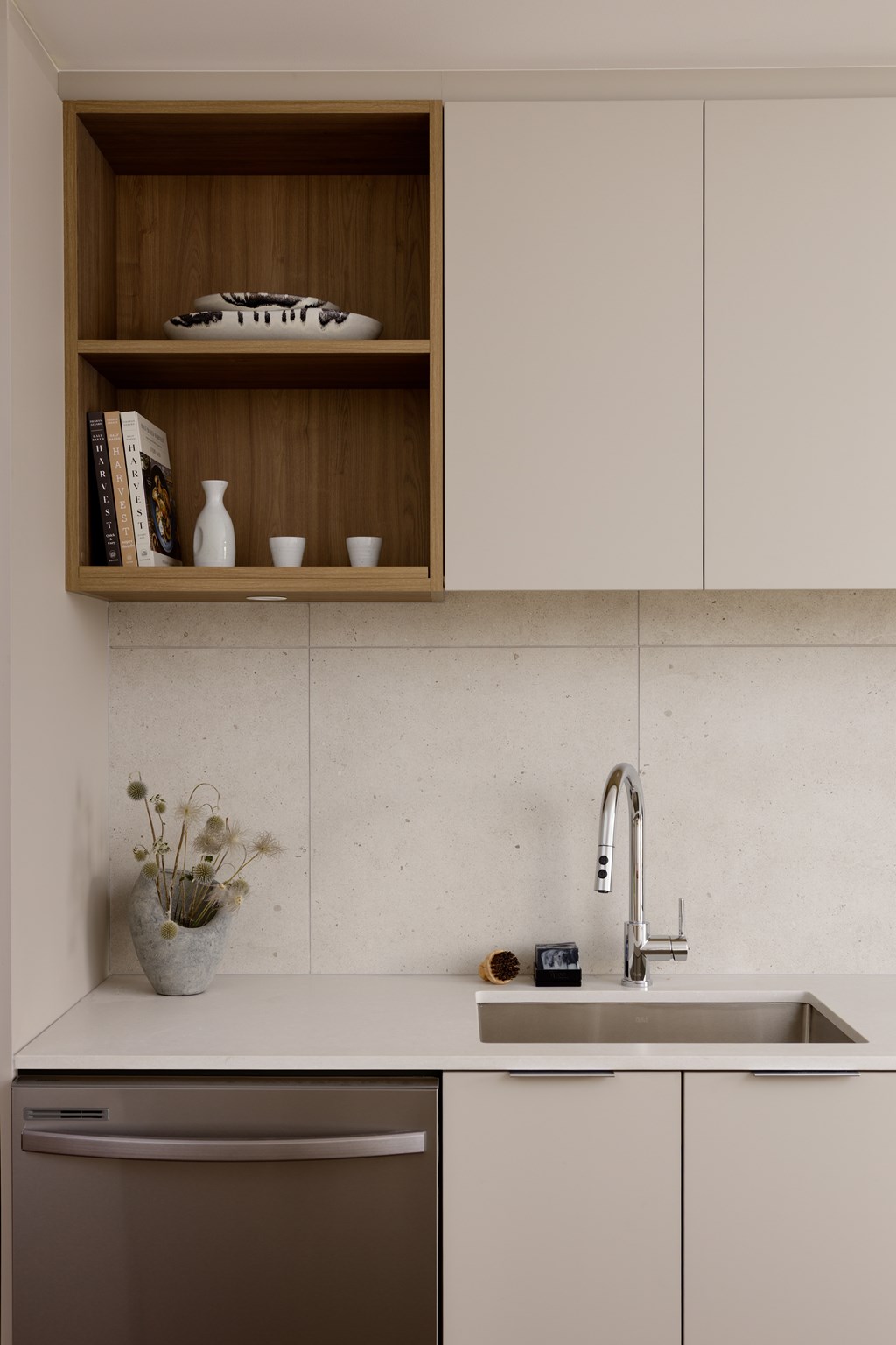 A kitchen with a sink, dishwasher and a shelf above the counter.