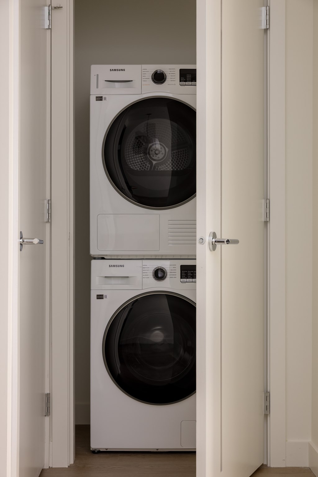 Two white front loading washing machines in a small room.