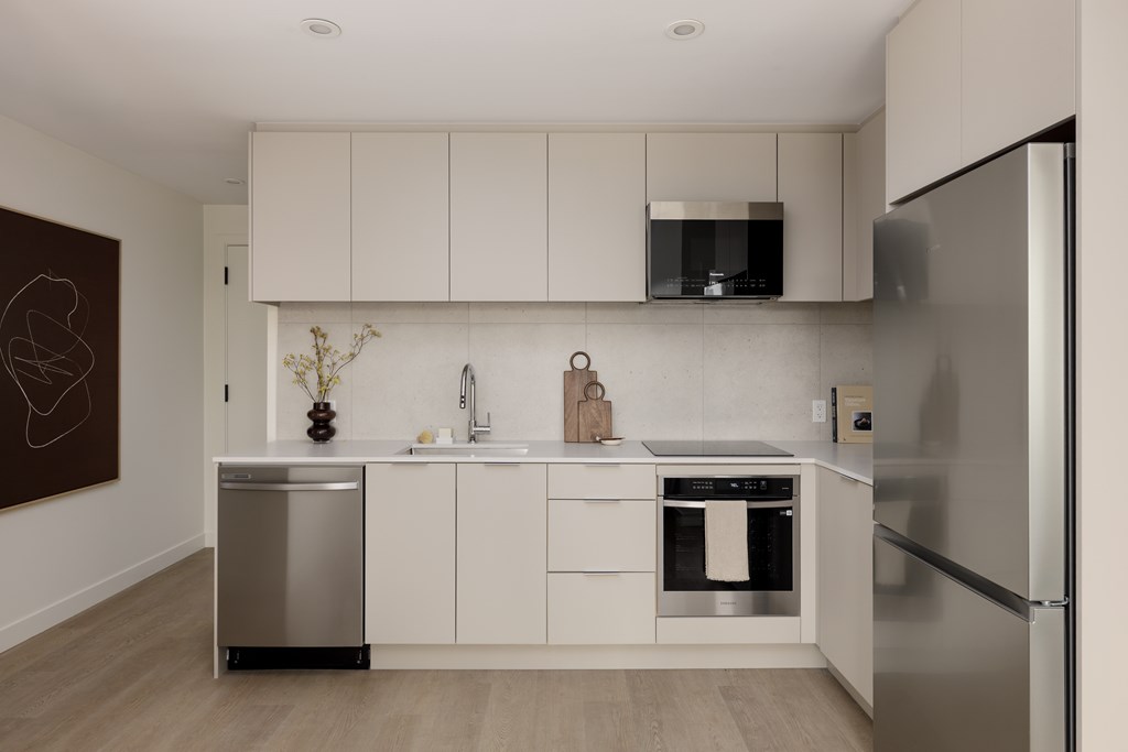 A modern kitchen with white cabinets and stainless steel appliances.