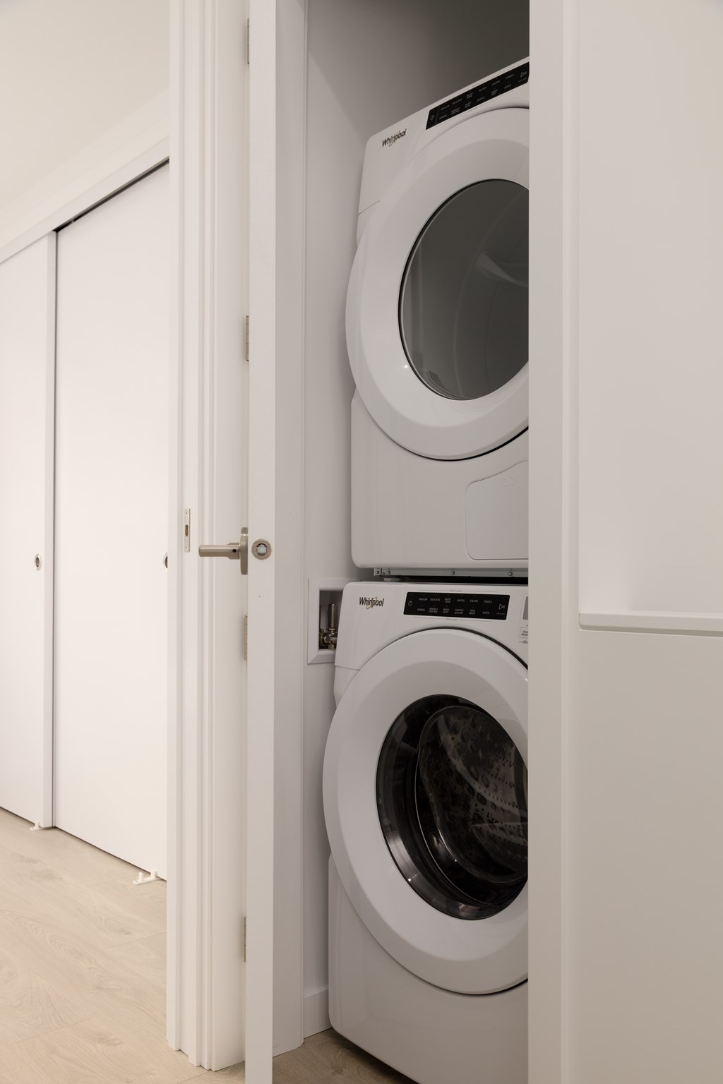 A white washing machine is in a white cabinet.