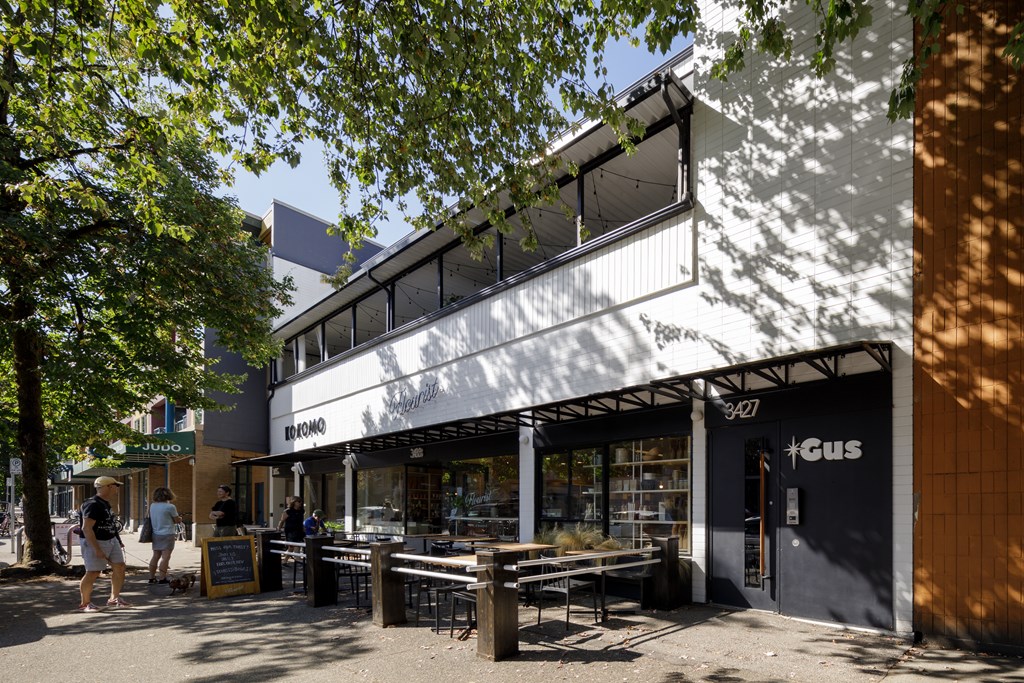 A white building with a black door and windows with a sign that says "cus" on it.
