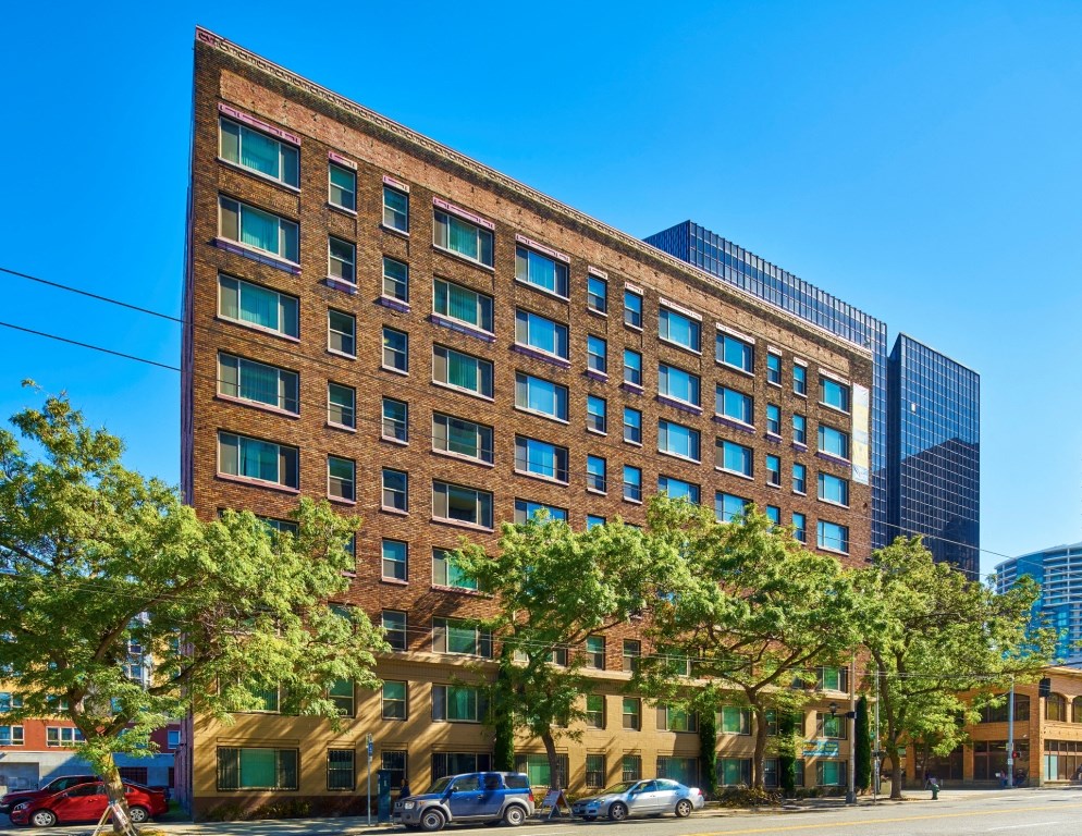 A large brick building with many windows and trees in front.