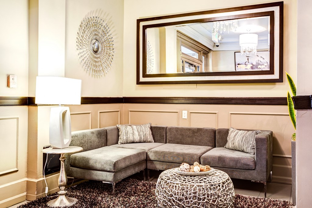 Apartment lobby with a grey couch and a round table.