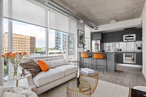 A modern living room with a white sofa and a kitchen area in the background.