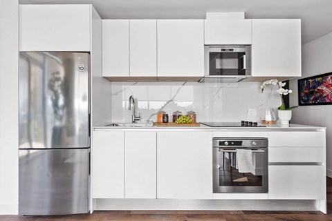 A modern kitchen with white cabinets and stainless steel appliances.