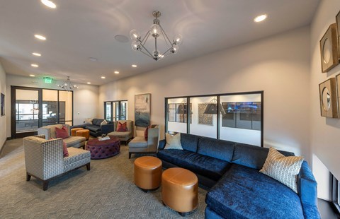 A living room with a blue couch and a brown ottoman.