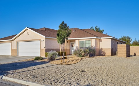 A house with a brown roof and tan walls with a white garage door.