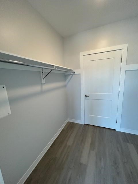 A white door is in a room with a grey floor and a grey wall.