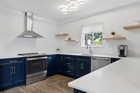 A modern kitchen with dark blue cabinets and stainless steel appliances.