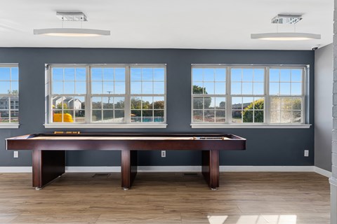 A room with a pool table and a view of the outside through the windows.