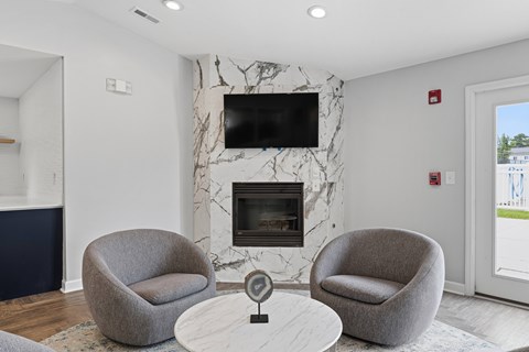 A living room with a fireplace and two grey armchairs.