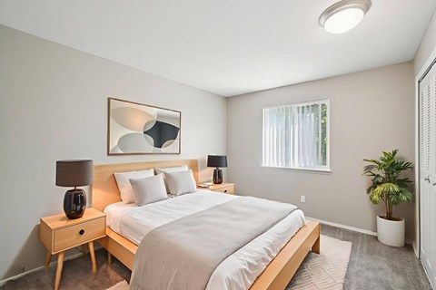 A bedroom with a bed, nightstands, and a plant.