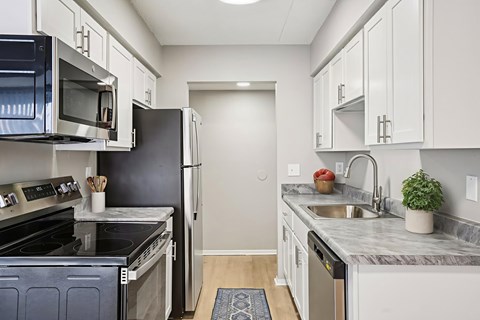 A kitchen with white cabinets and a black refrigerator.
