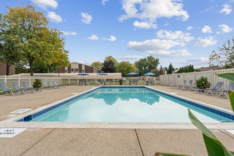 A large swimming pool surrounded by chairs and trees.
