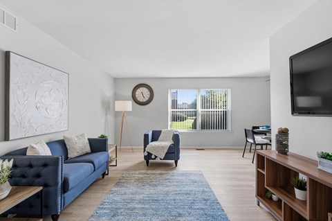 A living room with a blue couch and a wooden floor.
