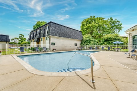Outdoor swimming pool with sundeck and seating at Hampton Court Apartments, Westland, MI