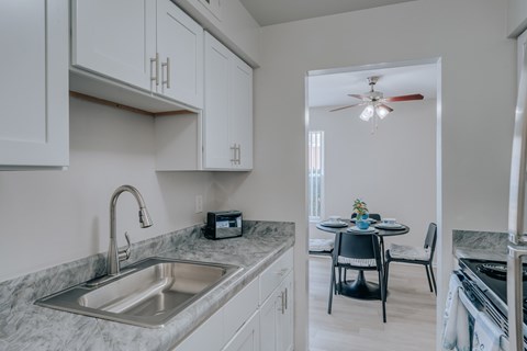 Modern kitchen with stainless steel sink and dining area at Canterbury Square Apartments, Troy, Michigan