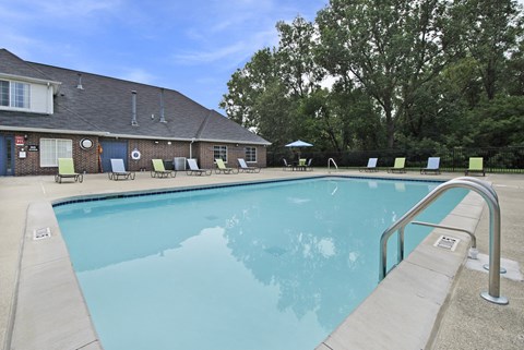 Outdoor swimming pool with lounge chairs and umbrella at Bloomfield Villas Apartments, Auburn Hills