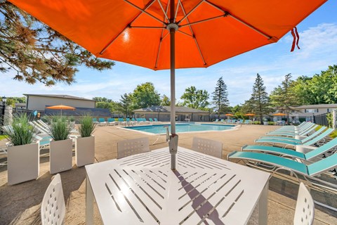 Pool patio with white table chairs and orange umbrella at Cambridge on Ford Apartments, Canton, 48187