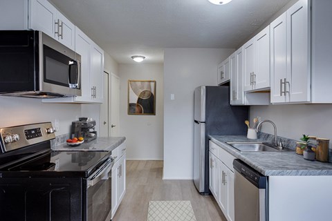 A kitchen with black appliances and white cabinets.