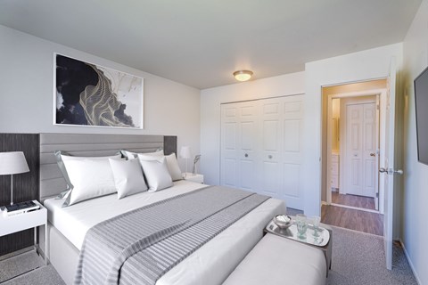 A bedroom with a large bed and a painting on the wall.