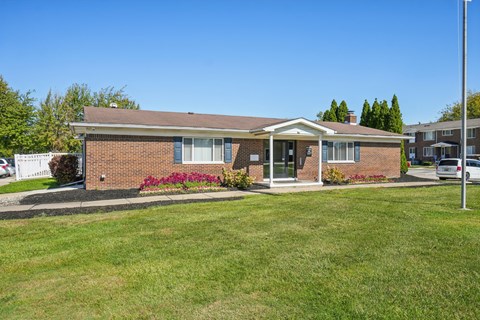 A small brick house with a front porch and a green lawn.