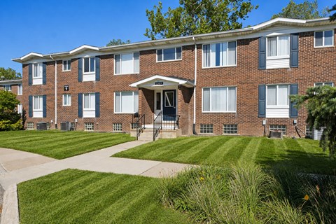 A brick apartment building with a green lawn in front.