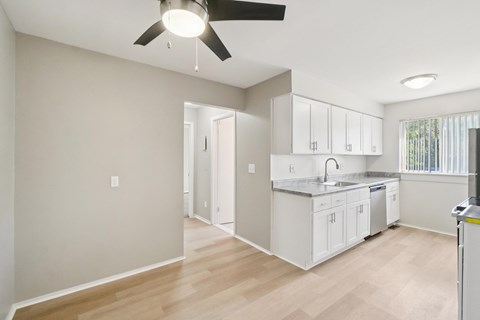 A kitchen with white cabinets and a ceiling fan.