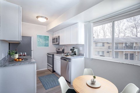 A kitchen with a table and chairs and a fridge.