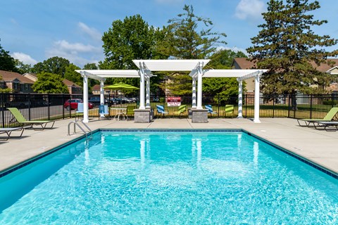 A pool with a white pergola over it.
