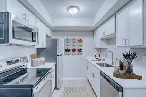 A modern kitchen with white cabinets and stainless steel appliances.