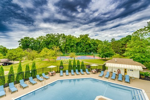 Pool deck with lounge chairs and tennis courts at Valley Ranch Apartments, Michigan