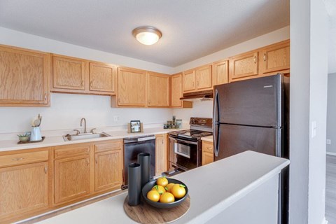 A kitchen with wooden cabinets and a black refrigerator.