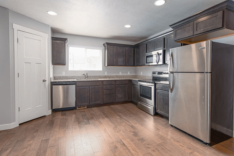A kitchen with a stainless steel refrigerator, oven, and microwave.