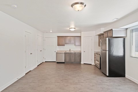 A kitchen with a black refrigerator and white walls.