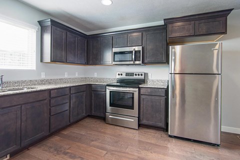 A kitchen with dark wood cabinets and stainless steel appliances.