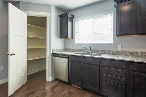 A kitchen with dark wood cabinets and a granite countertop.