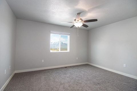 A room with a ceiling fan and a window showing a mountain view.