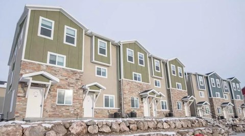 A row of houses with grey and green siding.