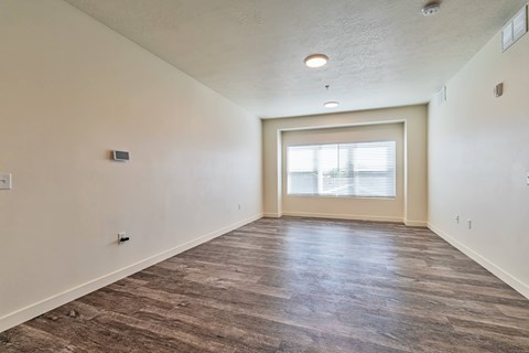 A room with a wooden floor and a window with blinds.