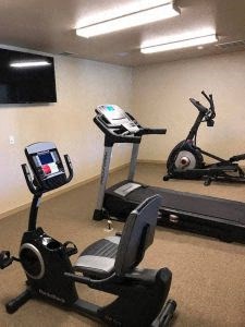 a room filled with lots of exercise equipment and a flat screen tv