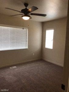 an empty room with a ceiling fan and a window