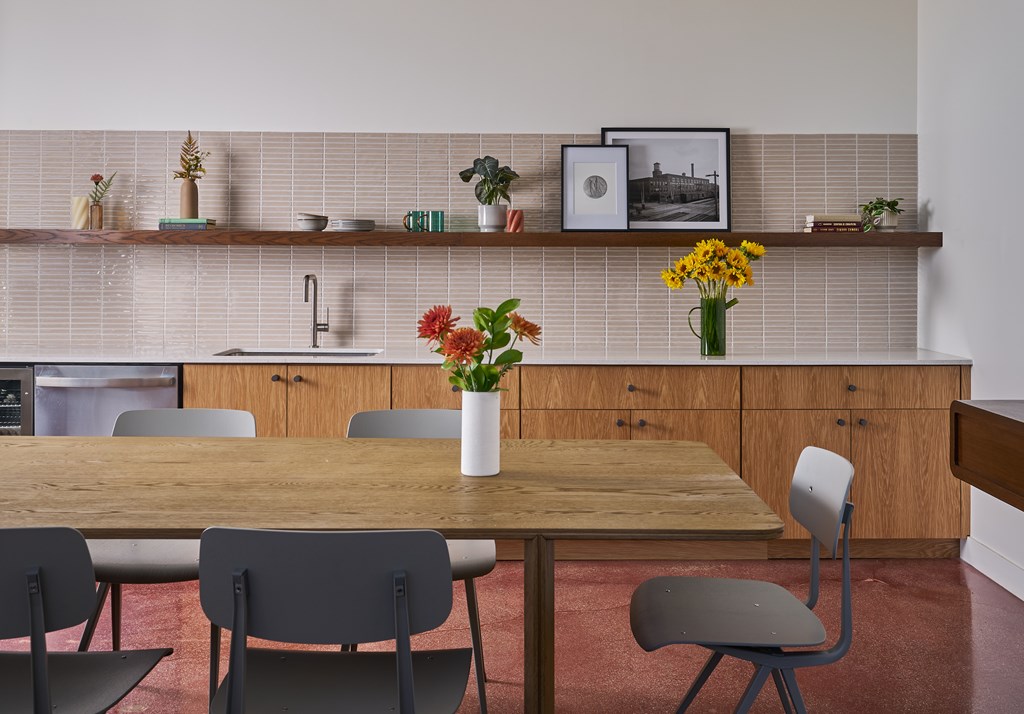 A kitchen with a table and chairs and a vase of flowers on the table.