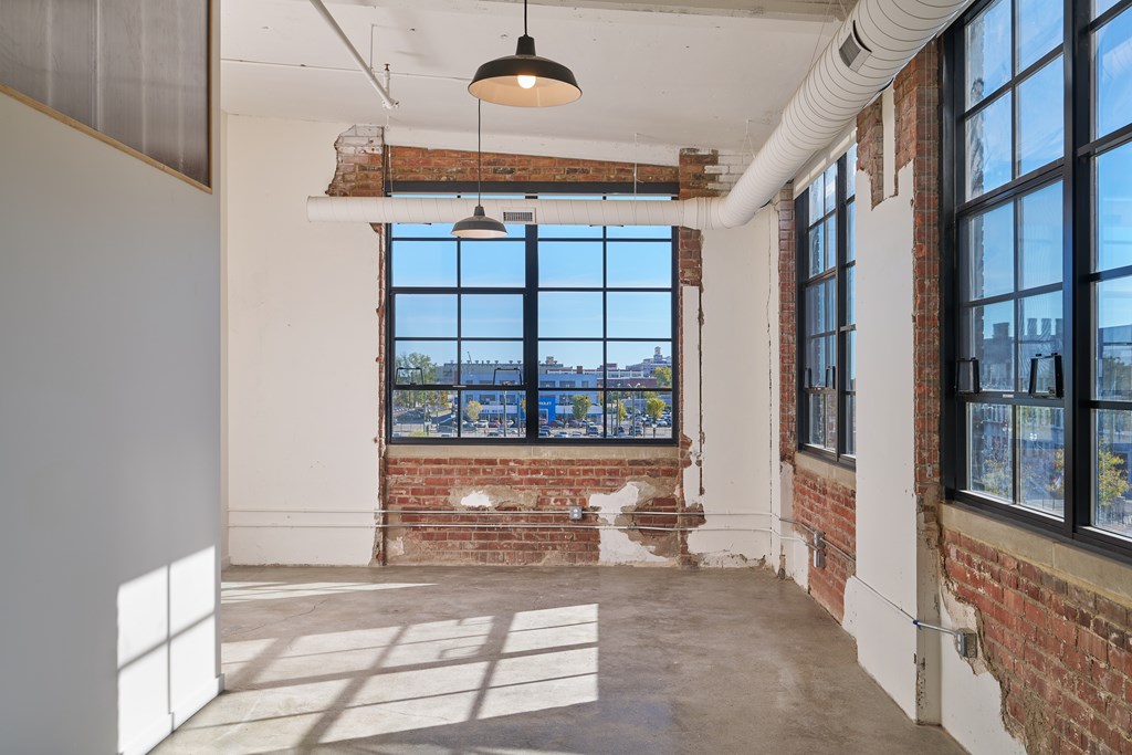 A room with a large window and a brick wall.