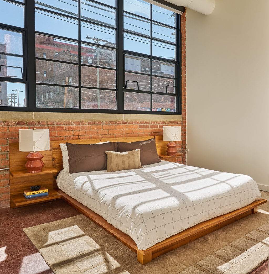 A bedroom with a large bed and a brick wall.