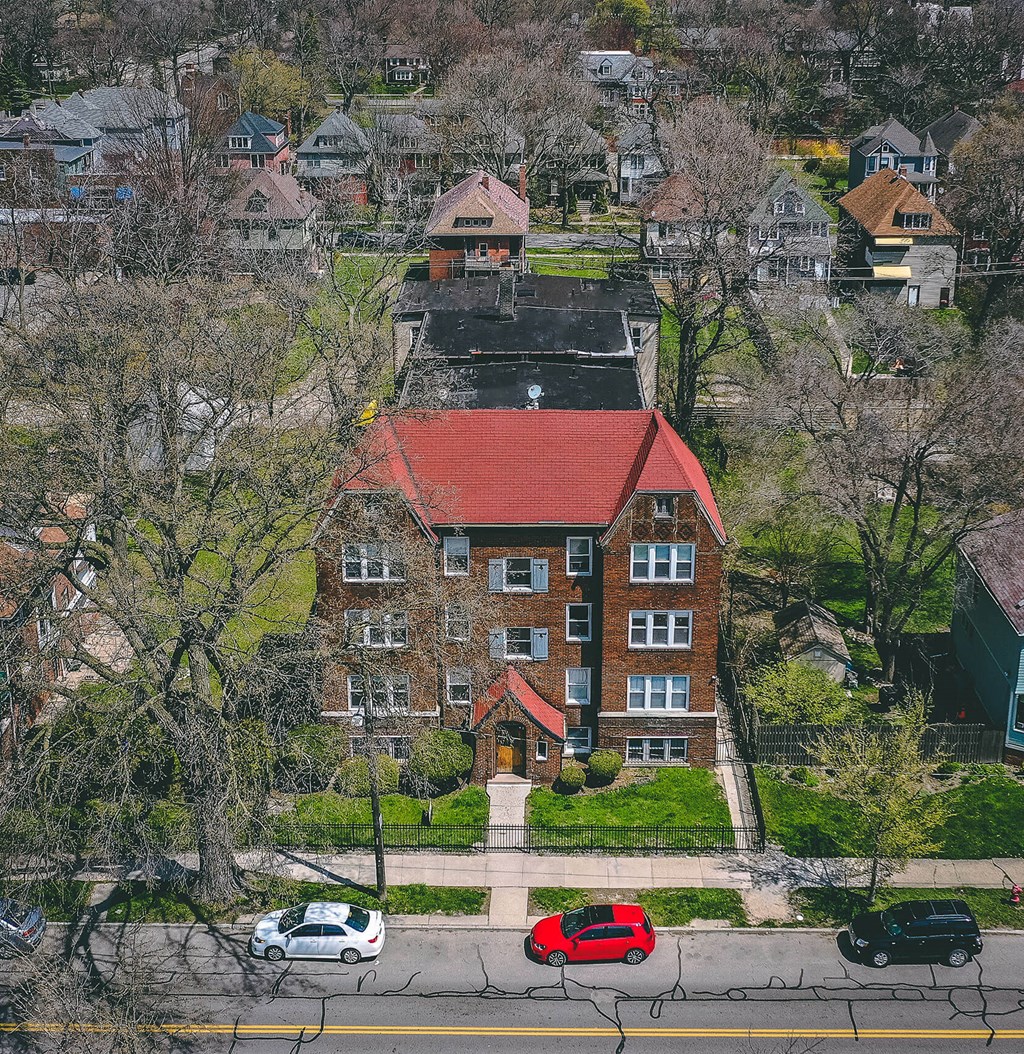 A red car is parked on the street in front of a brick building.