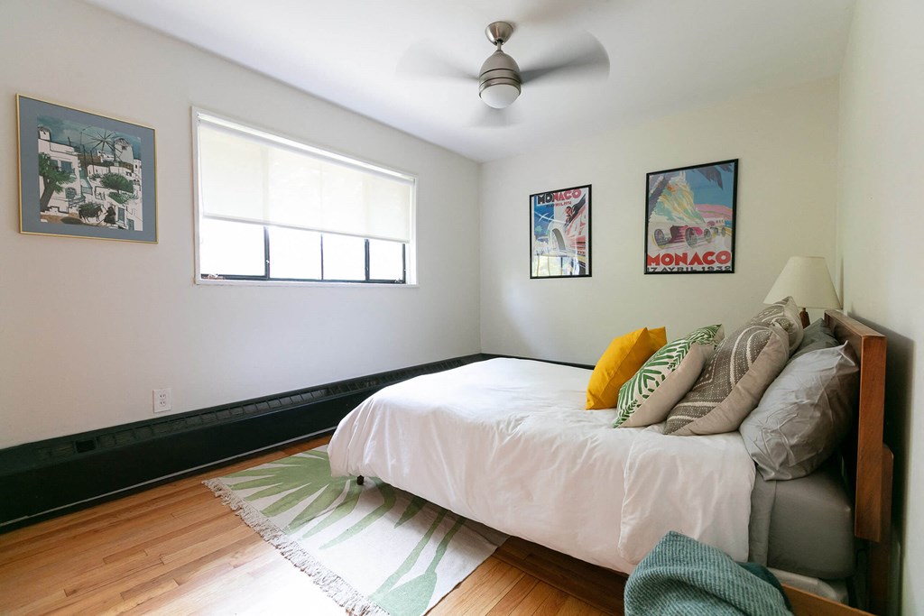 A bedroom with a bed, a ceiling fan, and two posters on the wall.