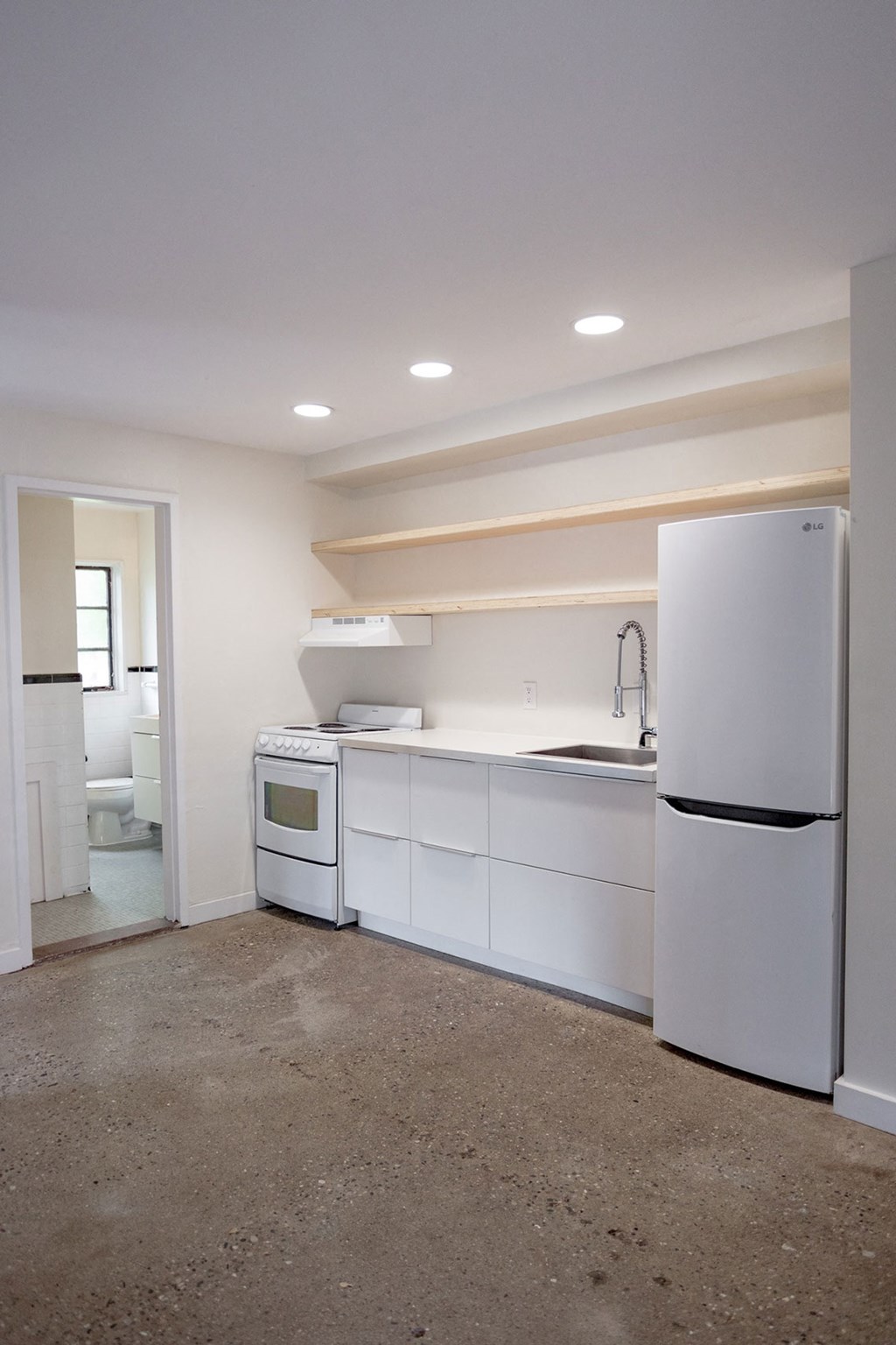 A white kitchen with a refrigerator, sink, and cabinets.