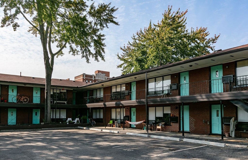 A tree stands in front of a building with balconies.